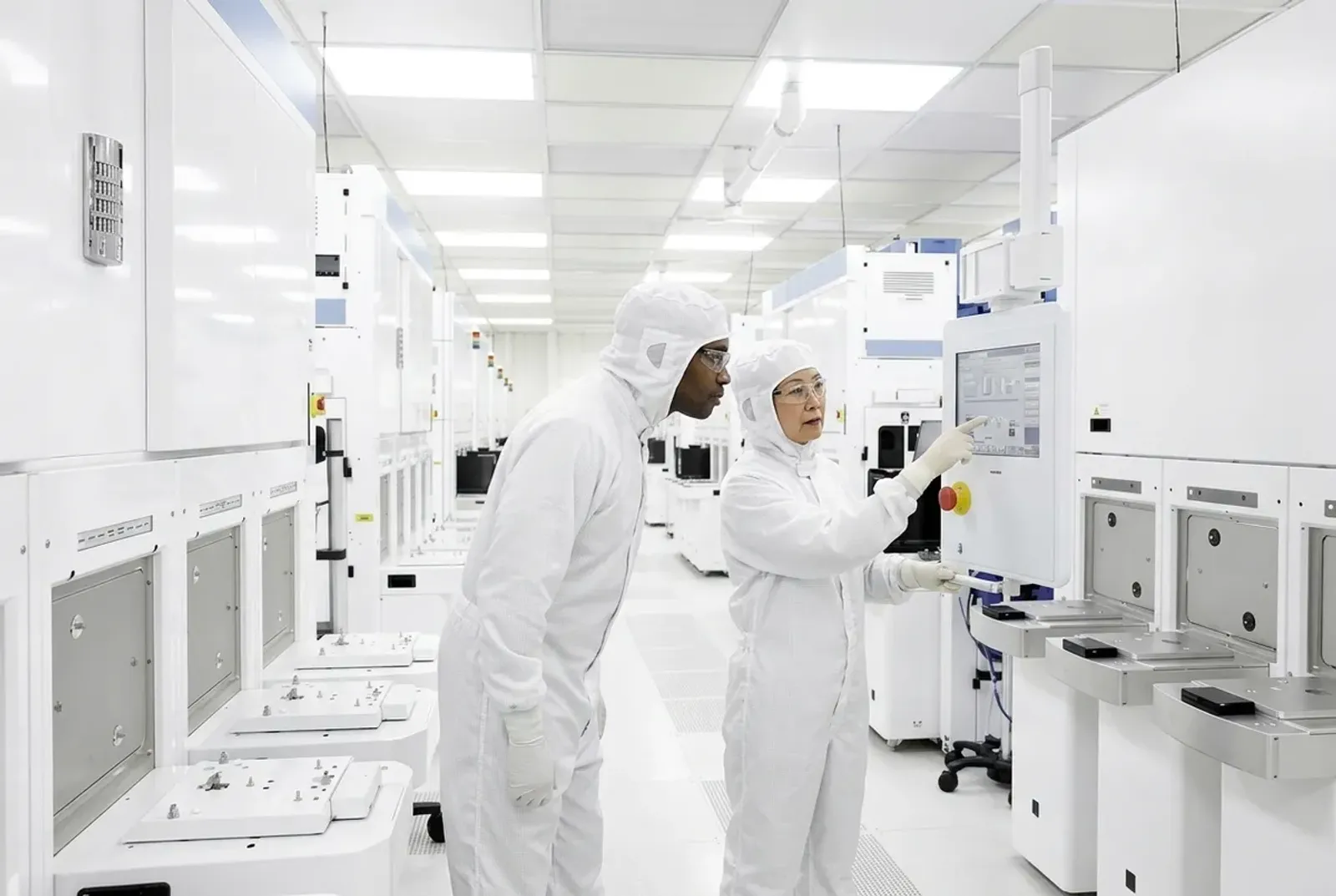 Senior cleanroom technician showing a colleague a procedure at a process tool