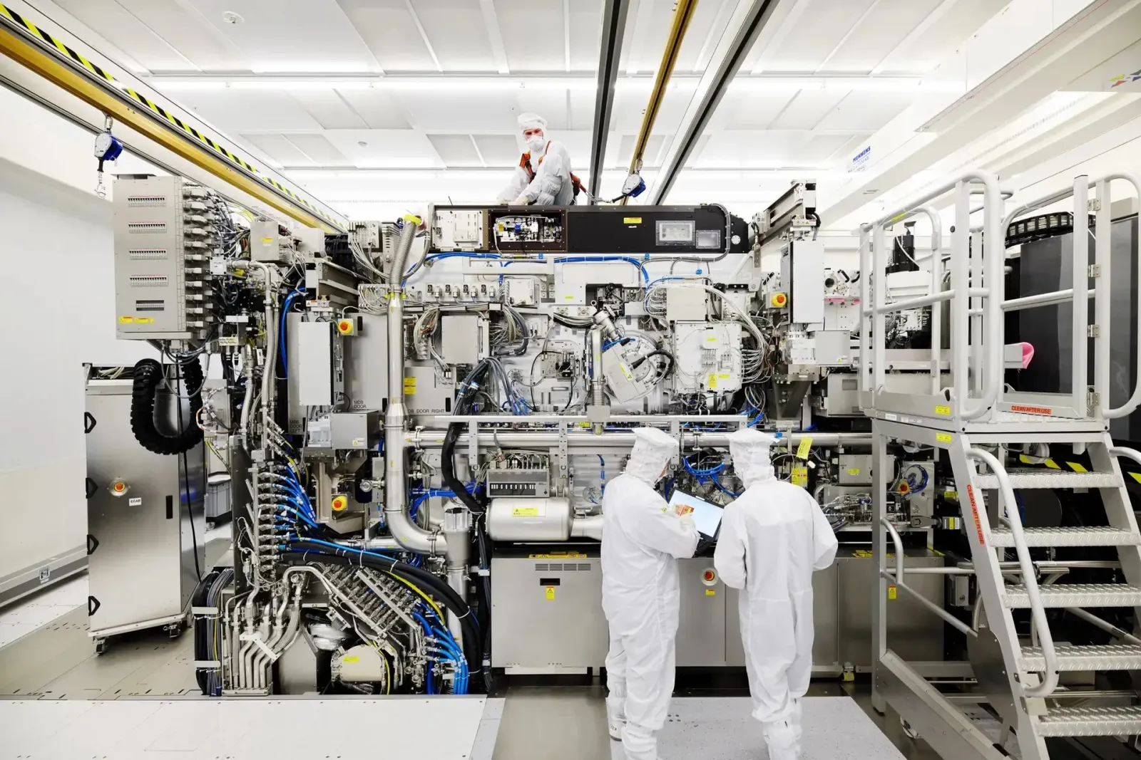 Technicians in cleanroom suits working on an advanced EUV lithography system
