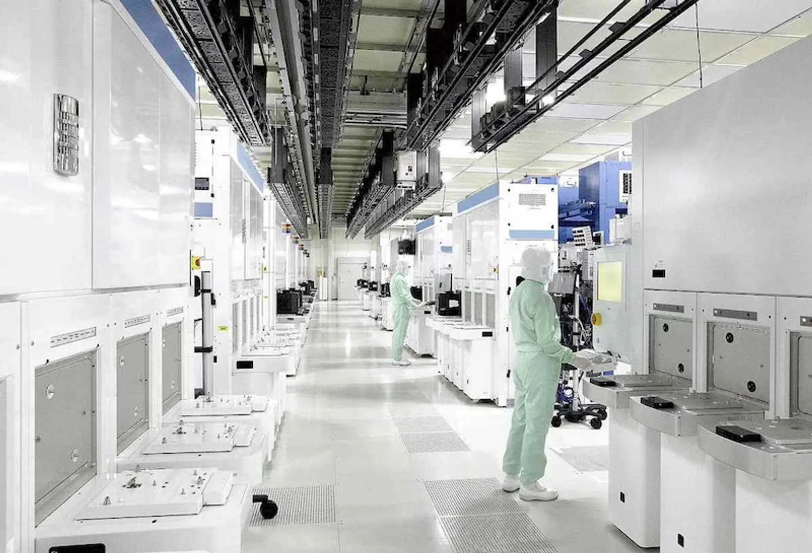 Technicians in cleanroom suits working in a semiconductor fab aisle