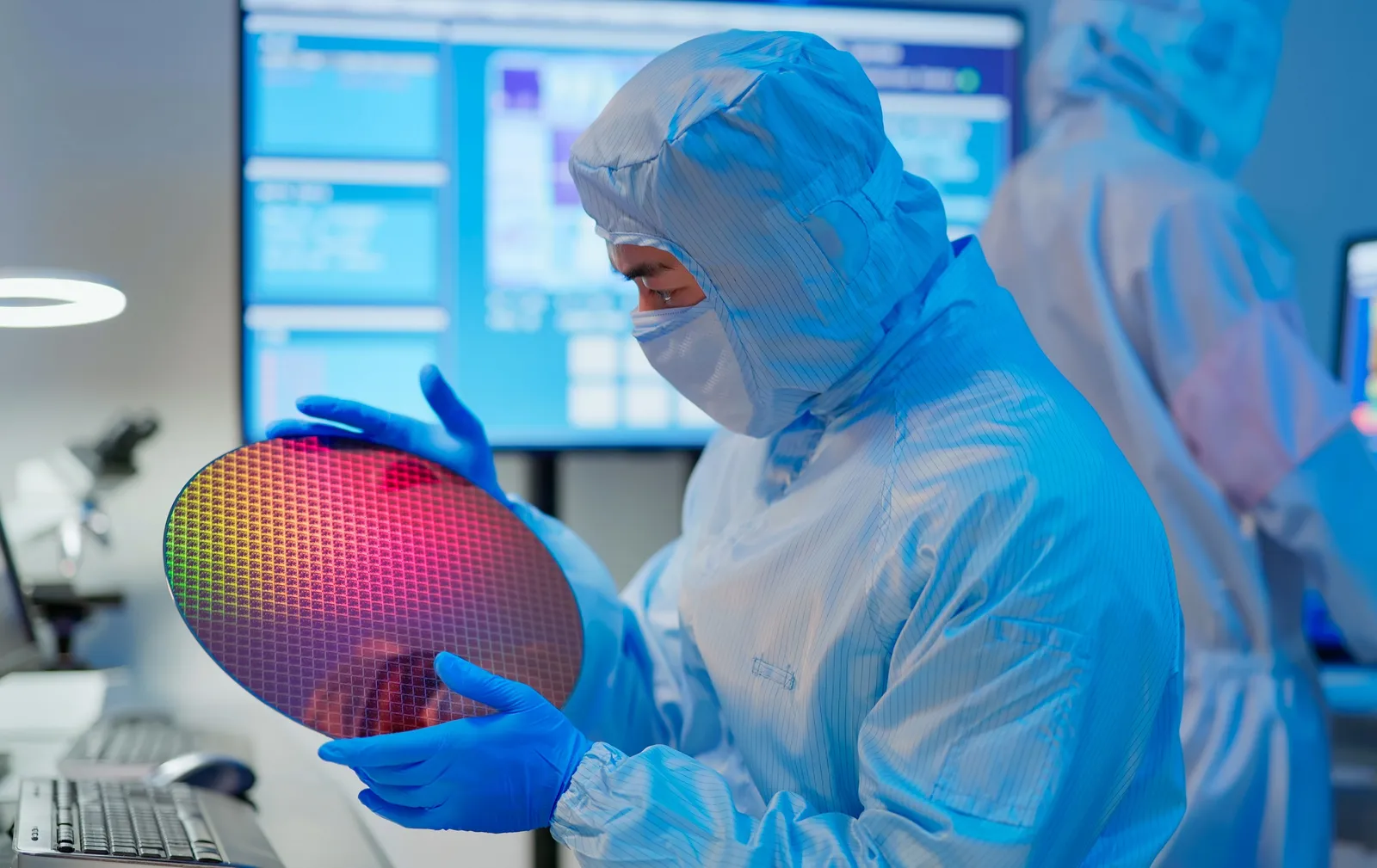 Technician inspecting a silicon wafer inside a semiconductor fab